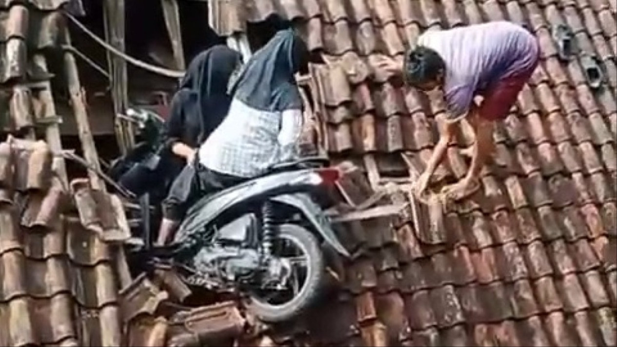 Motosikal budak perempuan tersangkut atas bumbung rumah