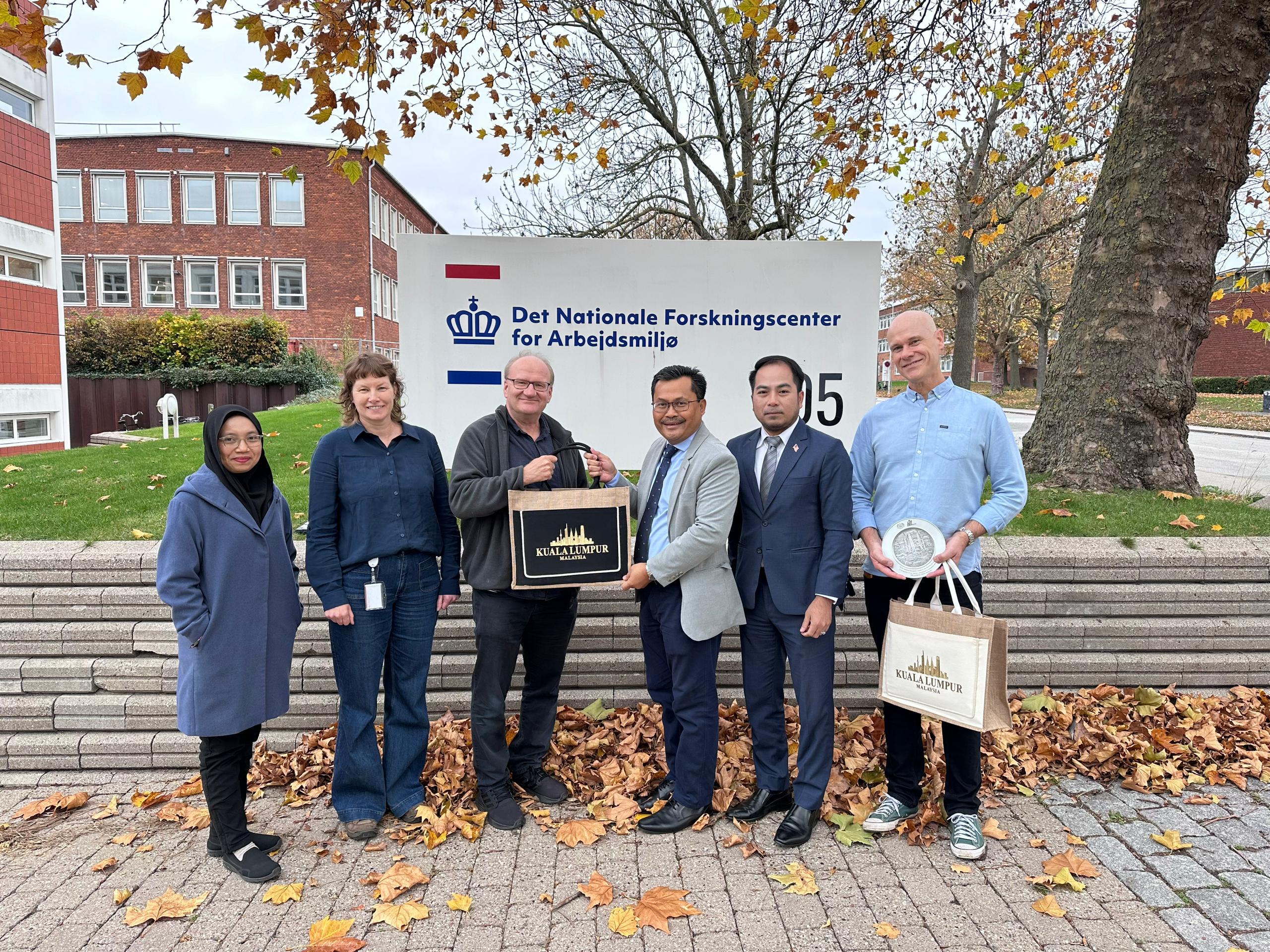 Ayop Salleh menyerahkan cenderahati NIOSH kepada Professor Keld Alstrup Jensen baju biru yang mewakili National Research Center for the Working Environment NFA Denmark.