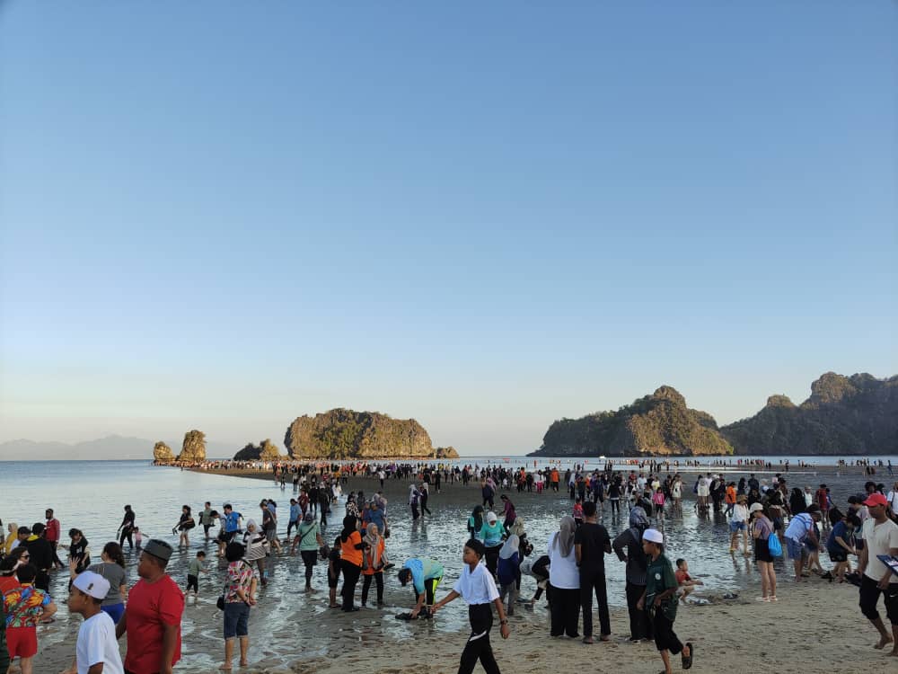 Orang ramai berjalan di atas beting pasir yang terbentuk berikutan fenomena air surut penuh di Pantai Tanjung Rhu Langkawi pagi ini.